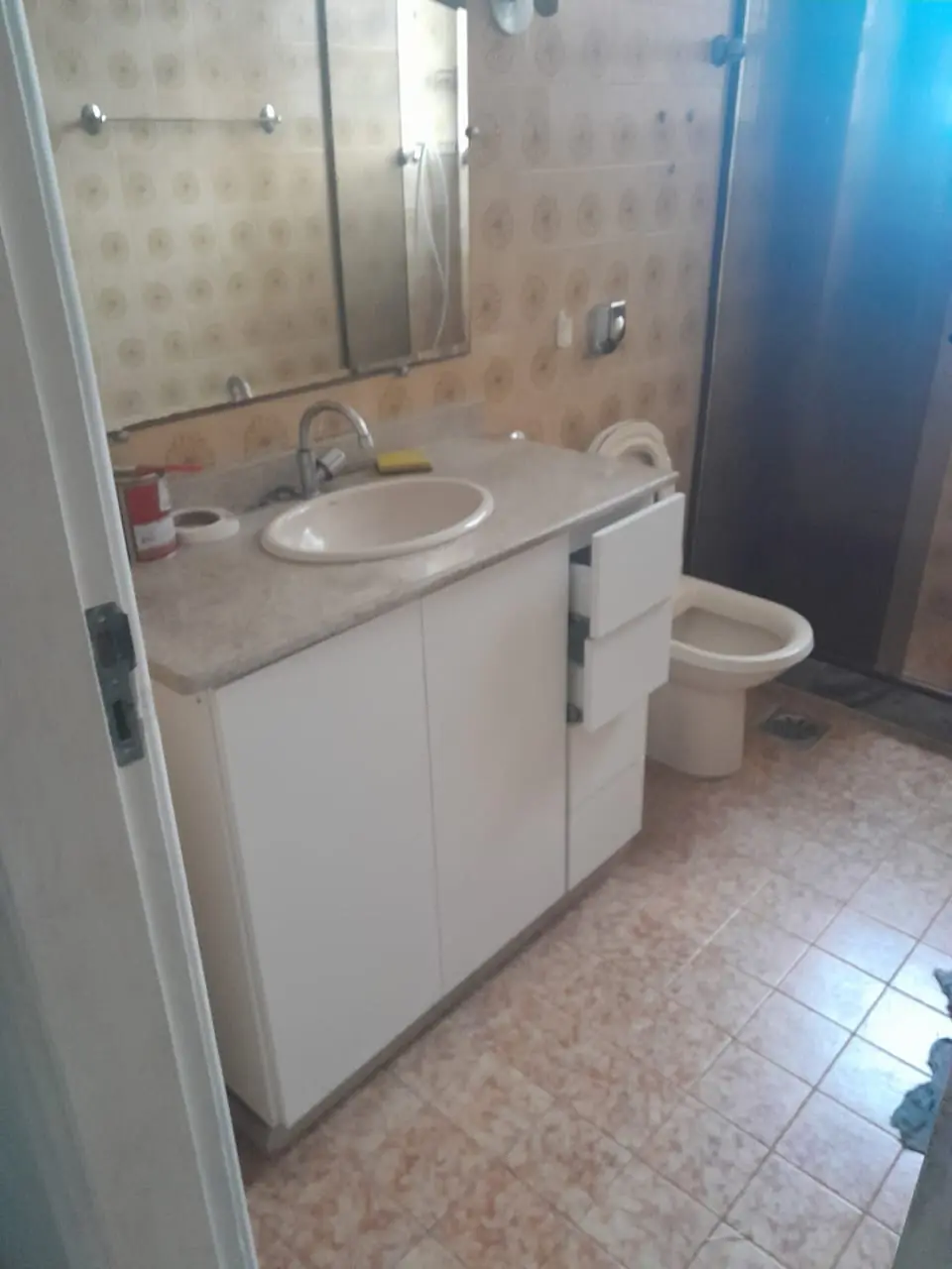 Banheiro com gabinete branco instalado sob a pia